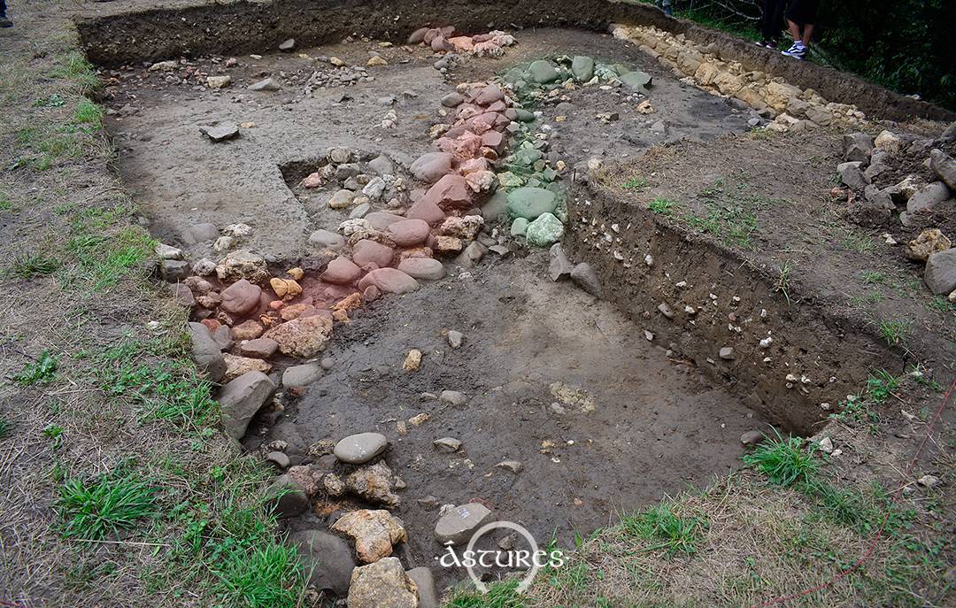 En la foto he coloreado los zócalos de piedra de las dos construcciones documentadas en la excavación de Antrialgo 2025. La de color rojo se superpone a la verde por lo que es más reciente. Incluso la muralla corta esa construcción por lo que podría pensarse que es de una fase anterior a su edificación final.
